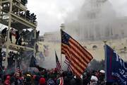 Supporters of then-President Donald Trump gather in front of the U.S. Capitol in Washington Jan. 6, 2021, holding a large 13-star flag amid smoke.