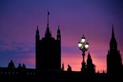People cross London’s Westminster Bridge as the Houses of Parliament are pictured silhouetted at sunset Dec. 4, 2020.