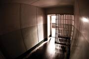 Stock photo of an empty prison cell with the door slightly open.