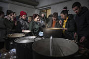 People line up to receive hot food in an improvised bomb shelter in Mariupol, Ukraine, on March 7, 2022. (AP Photo/Evgeniy Maloletka)