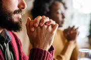 Stock image of a man and woman with hands folded in prayer.