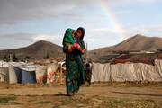 A young, internally displaced Afghan woman carries a child near their shelter at a camp on the outskirts of Kabul in June 2019. (CNS photo/Omar Sobhani, Reuters)