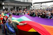 people standing around a large pride flag of many colors in belgium in may 2018