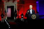 joe biden stands while giving his speech on maga republicans, the background behind him is red with an american flag