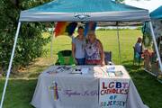 two people standing under an awning with an lgbt catholics of new jersey sign in front of them