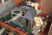 Three men put metal sheets on the roof of a shed 
