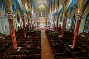 looking down at a church with gothic style architecture with about 50 people inside during a mass