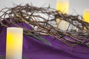 crown of thorns on a purple background with a candle in front