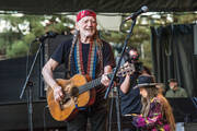 A smiling Willie Nelson playing his guitar Trigger at a recent concert. 