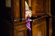 A photograph of a priest's hands praying the roasry while seated in a confessional
