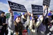 two girls hold signs that read "i am the post-roe generation" at the march for life in dc in 2023