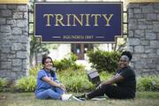 Two young women sit on the grass beneath the main entrance sign to Trinity Washington University, in Washington D.C., and smile toward the camera. (CNS photo/Tyler Orsburn)