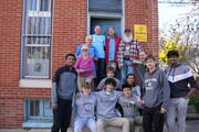 Students from Fordham Prep and other Viva House volunteers join Brendan Walsh, at left in dark blue shirt, and his wife Willa Bickham, standing below, on the steps of Viva House in Baltimore, Md., in March 2023.