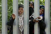 A view of migrants behind the metal barrier border that Poland has erected along the border with Belarus, in Bialowieza Forest, on May 29. Poland says neighboring Belarus and its main supporter Russia are behind a surging push by migrants in Belarus toward the European Union. (AP Photo/Czarek Sokolowski)