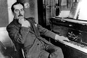 A historical photo of the Italian opera composer Giacomo Puccini seated at a piano.