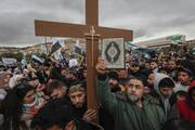 Syrians hold a copy of the Quran next to a Christian cross during a demonstration in support of unity among minorities and the ousting of the Bashar Assad government in Umayyad Square in Damascus, Syria, Friday, Dec. 27, 2024. (AP Photo/Omar Sanadiki)
