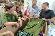 At a CEPA immersion tour in North Carolina in 2023, Sarah Richards (left), from the University of Dayton, listens in as Eric Henry (far right), president of TS Designs, describes how an ethical supply chain delivers college swag to Dayton students.