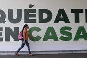 In Mexico City on March 31 a woman walks past a sign that urges: “Stay home.” Mexico's government broadened its shutdown of “non essential activities” and prohibited gatherings of more than 50 people to help slow down the spread of the new coronavirus. (AP Photo/Eduardo Verdugo)