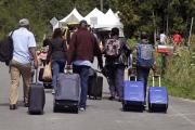 A family from Haiti approach a tent in Saint-Bernard-de-Lacolle, Quebec, stationed by Royal Canadian Mounted Police, as they haul their luggage down Roxham Road in Champlain, N.Y., Monday, Aug. 7, 2017. (AP Photo/Charles Krupa)