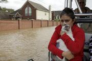 A woman holds her cat as she rides a boat out of her flooded Houston neighborhood on Aug. 29. (AP Photo/Charlie Riedel)