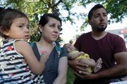 Pepe Urzua, a roofer who arrived from Mexico eight years ago, cradles his two-month-old daughter, Luna, as his wife, Betty, holds their daughter, Scarlet, during the a street festival in Goshen, Ind., on June 1, 2018. (AP Photo/Charles Rex Arbogast)