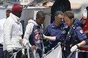 Italian coast guards instruct immigrants as they disembark from a coast guard ship at port in Lampedusa, Italy