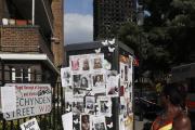 A woman looks towards missing posters stuck on a phone box in front of the remains of Grenfell Tower in London on June 17, 2017. ﻿﻿Police say it will take weeks or longer to recover and identify all the dead in the public housing block fire. (AP Photo/Kirsty Wigglesworth)