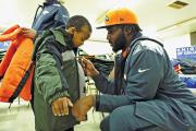HELPING HAND. Denver Broncos defensive end Robert Ayers helps a boy at the Knights of Columbus Coats for Kids event in Jersey City, N.J., in 2014.