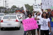 Police cars pass demonstrators on July 6 in Baton Rouge, La. Alton Sterling, a black man, was shot and killed by two white officers on July 5 outside a convenience store (AP Photo/Gerald Herbert).