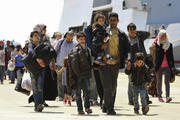 Migrants walk as they disembark from navy ship in Sicilian harbor of Augusta.