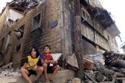 Their City in Ruins: Children sit among rubble in a besieged neighborhood in Homs, Syria, on Sept. 19