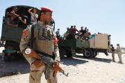 ON GAURD. An Iraqi soldier stands before truckloads of volunteers in Baghdad on June 17, eager to fight Sunni militants converging on the city. 