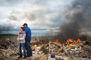 A father hugs his daughter while taking a break from helping friends sift though rubble from homes destroyed in an Arkansas tornado.