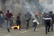 Supporters of opposition leader Henrique Capriles run from tear gas fired by riot police following voting in Caracas