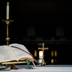 Opened book near gold-colored crucifix