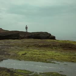 person standing on rock near body of water