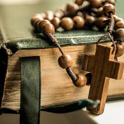 Brown prayer beads sitting on top of black book.