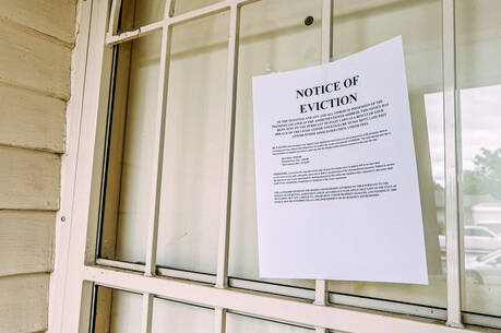 An eviction notice is taped to an iron gate in front of a white door with a peephole. (iStock/Jeremy Poland)