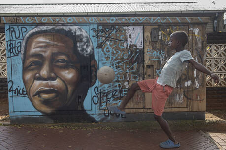 A child kicks a football in front of a mural of Nelson Mandela, in Soweto, South Africa, as the country celebrates Freedom Day on April 27. (AP Photo)
