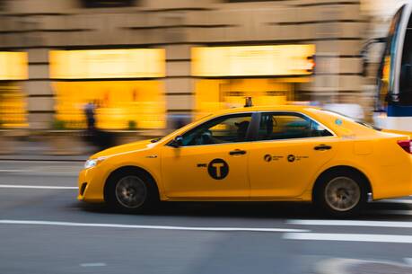 Stock image of a yellow taxi blurred as it speeds down the road.
