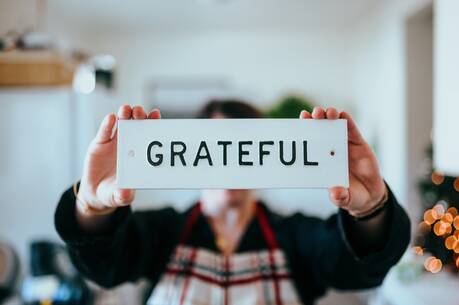 person holding white and black 'grateful' card