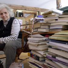 Grace Paley sits beside a pile of books in her home in Thetford Hill, Vt., April 9, 2003 (AP Photo/Toby Talbot).