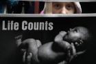 A young girl peeks through signs she is holding as she walks through downtown Chicago during the city's Jan. 18 March for Life. The marchers were calling for an end to abortion. (CNS photo/Karen Callaway, Catholic New World) 