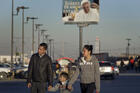 People walk in the parking lot of a shopping mall in front of a billboard with an image of Pope Francis in a working class neighborhood of Ciudad Juarez, Mexico. The pontiff is scheduled to visit the city on Feb. 17. (CNS photo/David Maung)