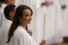 A new member of the church holds a candle as Pope Francis celebrates the Easter Vigil in St. Peter's Basilica at the Vatican March 26. The pope baptized 12 people at the vigil. (CNS photo/Paul Haring)