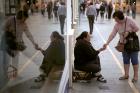 A woman gives a coin to a panhandler on Oct. 17 in Ronda, Spain. (CNS photo/Jon Nazca, Reuters)