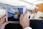 A journalist uses a tablet to photograph Pope Francis as he answers questions from journalists aboard his flight from Malmo, Sweden, to Rome Nov. 1. (CNS photo/Paul Haring) 