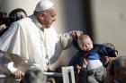 Pope Francis adjusts the hoodie of a baby during his general audience in St. Peter's Square at the Vatican on March 29. (CNS photo/Paul Haring)