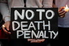 Filipinos light candles and hold a placard during a March 8 protest against the death penalty in Manila, Philippines (CNS photo/Mark R. Cristino, EPA). 