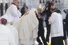 Pope Francis embraces Lucas Batista from Brazil as offertory gifts are presented during the canonization Mass of Sts. Francisco and Jacinta Marto.